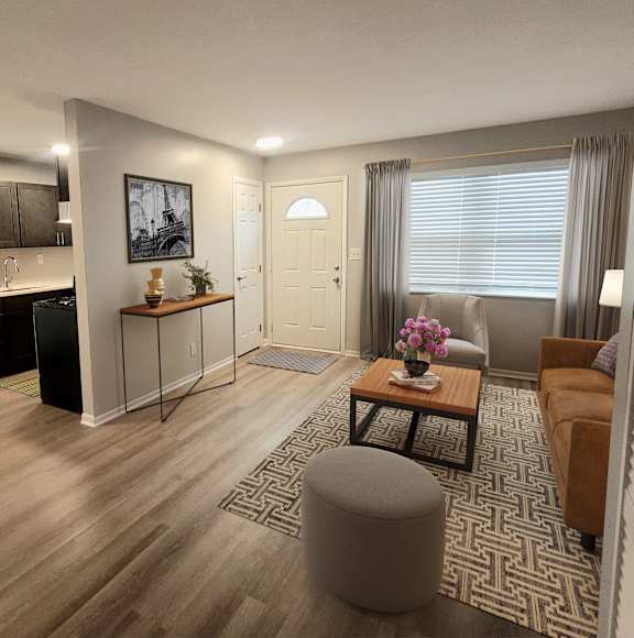 A living room with a brown sofa, a wooden coffee table, and a grey ottoman.