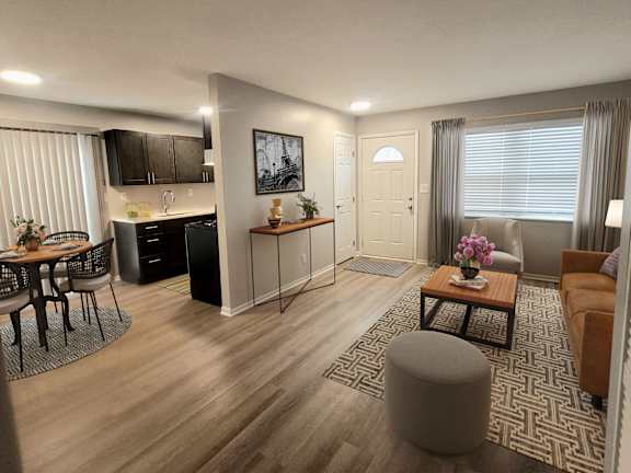 A modern living room with a kitchen area in the background.