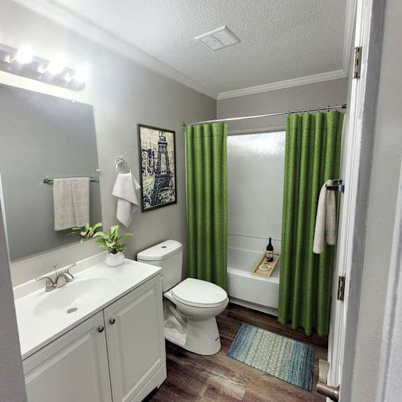 A white sink and toilet in a bathroom with green curtains.
