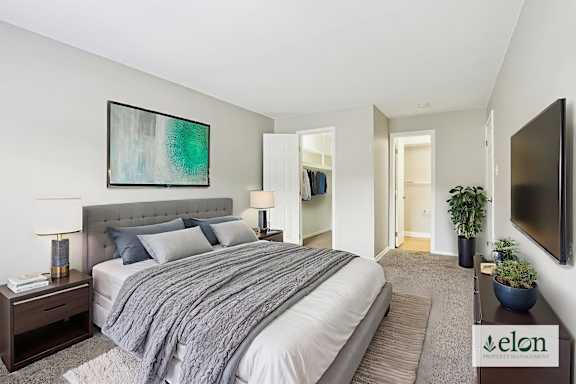 A bedroom with a large bed and a painting on the wall.