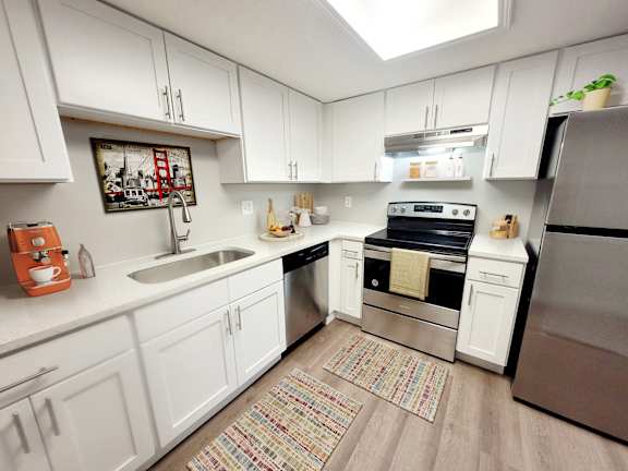A kitchen with white cabinets and a framed picture of the golden gate bridge on the wall.