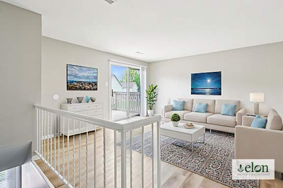 A living room with a white couch and a painting on the wall.