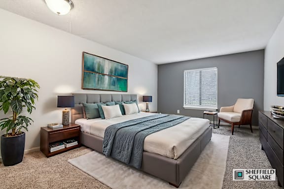 A bedroom with a large bed and a painting on the wall.