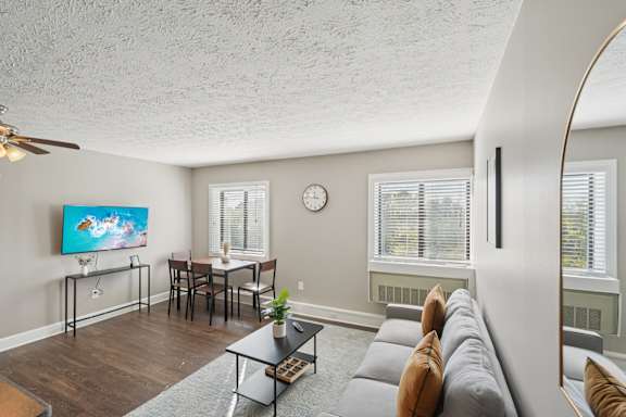 A living room with a grey couch and a painting on the wall.