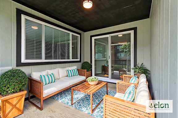 A patio with a couch, chairs, and a table with a bowl of fruit on it.