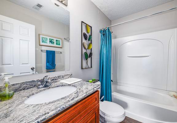 A bathroom with a marble countertop and a white bathtub.