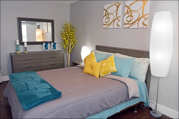 A bedroom with a bed, a dresser, a mirror, and a lamp.