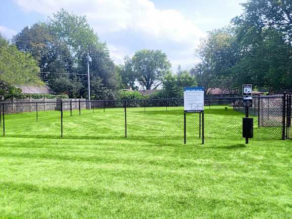 A sign is posted on a fence in a grassy field.