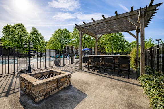 A patio area with a fire pit and a pergola.