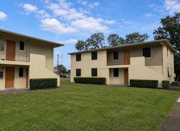 Two identical houses with brown doors and windows are situated on a grassy area.
