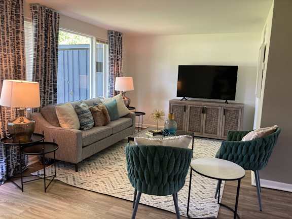 A living room with a grey couch, a green chair, a small table, and a television.