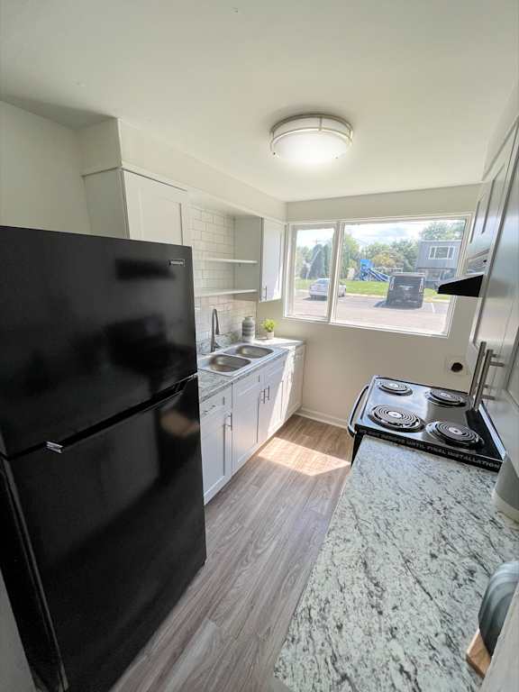 A black fridge in a kitchen with a black stove top.