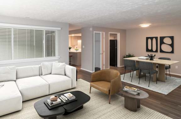 A living room with a white couch, a brown chair, and a black coffee table.