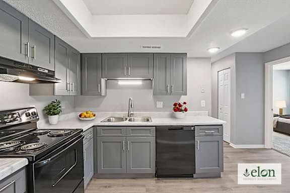 A modern kitchen with a stove top oven, sink, and cabinets.