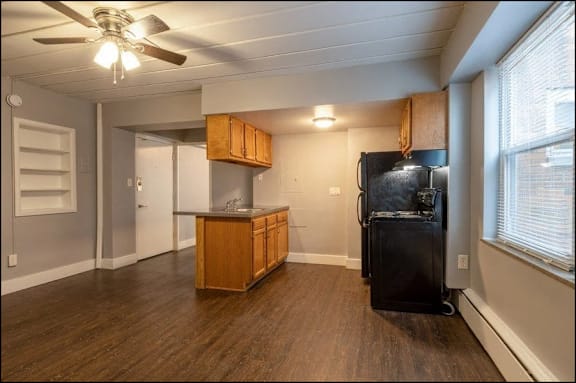 A kitchen with a black fridge and wooden cabinets.