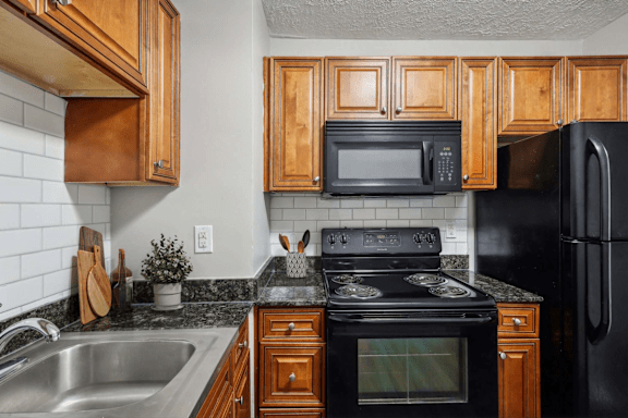A kitchen with black appliances and wooden cabinets.