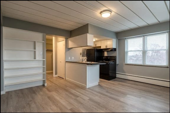 A kitchen with a black refrigerator and white cabinets.
