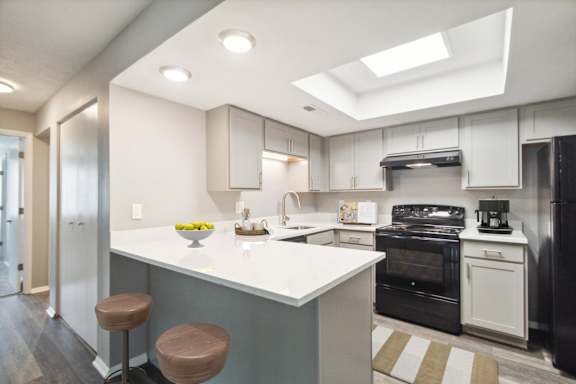 A kitchen with a white counter top and brown stools.
