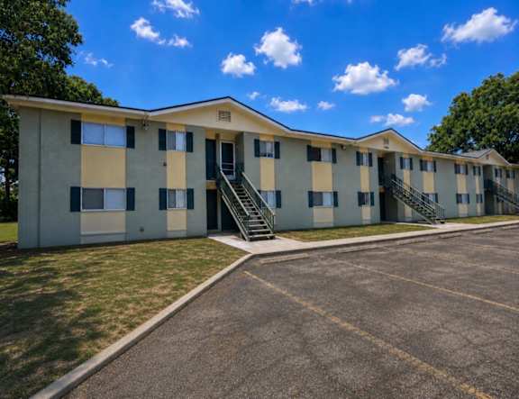 A large apartment complex with a parking lot in front.