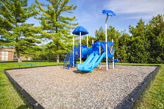 A playground with a blue slide and a blue umbrella.