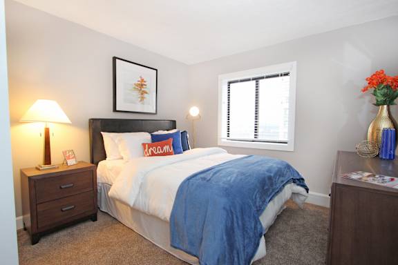 A bedroom with a bed, nightstand, and window.