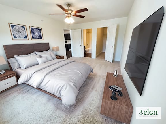 A bedroom with a large bed and a flat screen TV mounted on the wall.