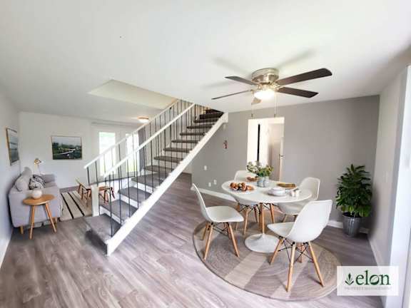 A dining room with a table set for four and a staircase.