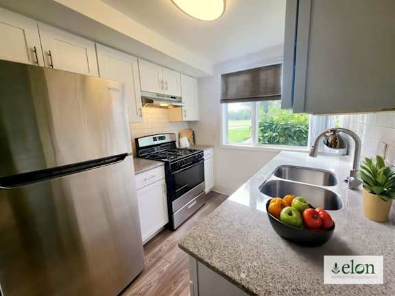 A modern kitchen with a stainless steel refrigerator and a bowl of fruit on the counter.