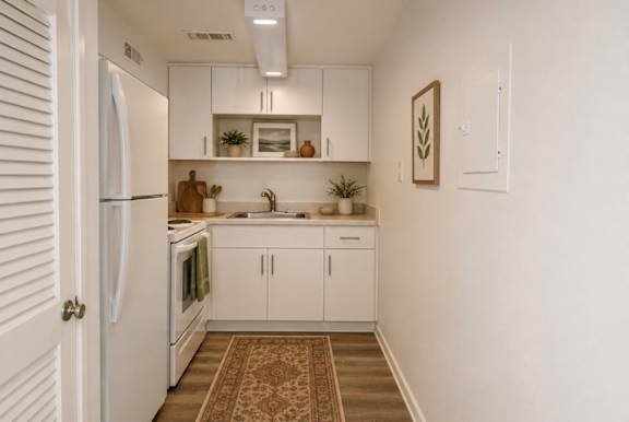 A kitchen with white cabinets and a rug on the floor.