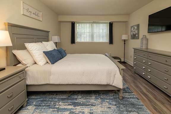 A bedroom with a bed, nightstands, and a dresser.at Deer Park Apartments, Maryland, 21133