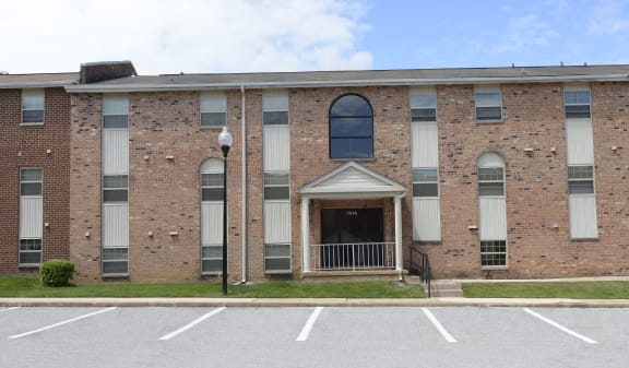 A large brick building with a parking lot in front of it at Liberty Gardens Apartments, Baltimore, MD