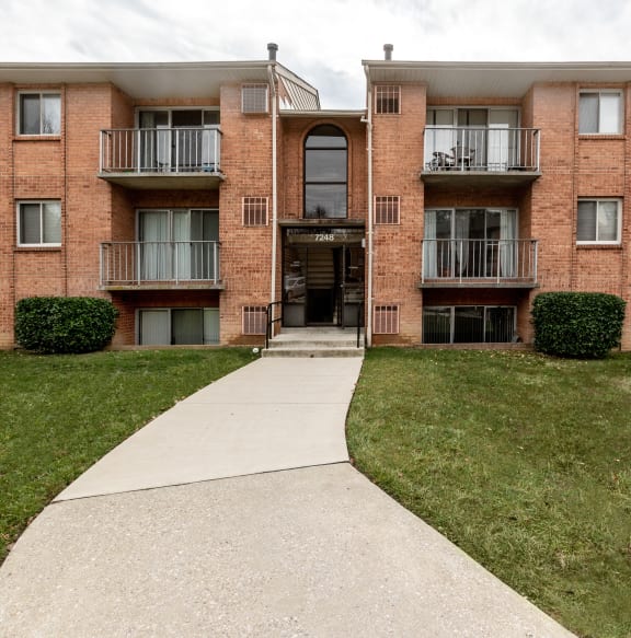 An apartment building with a concrete walkway at Lawyers Hill Apartments, Elkridge, MD