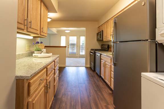 A kitchen with wooden cabinets and a stainless steel refrigerator at Charlesgate Apartments, Maryland, 21204