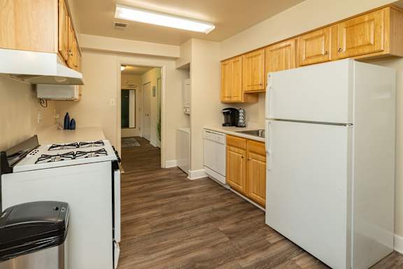 A kitchen with a white fridge and wooden cabinets.at Deer Park Apartments, Maryland