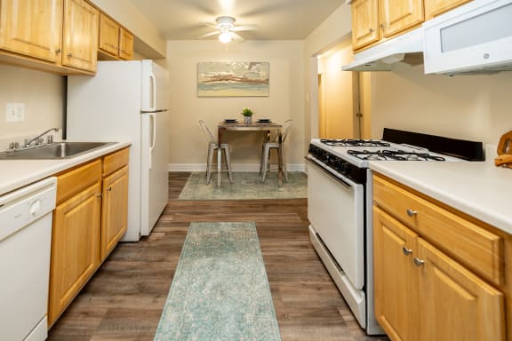 Kitchen with white appliances and wooden cabinets at Deer Park Apartments, Randallstown, MD