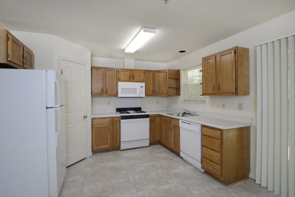 a kitchen with white appliances and wooden cabinets at Carlson Woods Townhomes, Baltimore