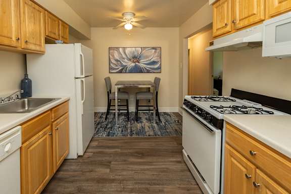 A kitchen with wooden cabinets and a white stove top oven.at Deer Park Apartments, Randallstown, MD