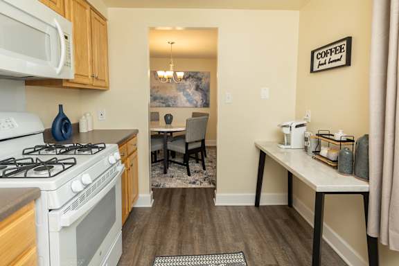 A kitchen with a white stove and a white microwave above it. at Colony Hill Apartments &amp; Townhomes, Baltimore, MD, 21227