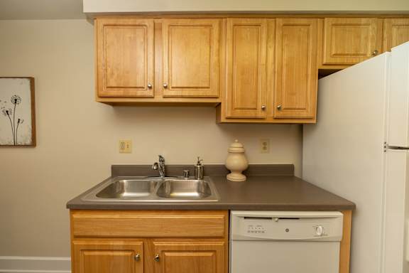 A kitchen with wooden cabinets and a white refrigerator.at Chapel Valley Townhomes, Nottingham, MD 21236