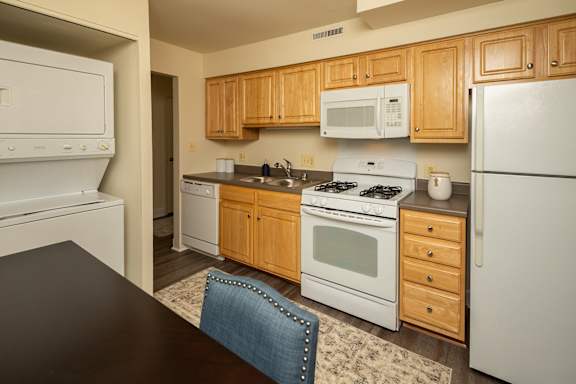 A kitchen with wooden cabinets and white appliances at The Brittany Apartments, Maryland, 21208