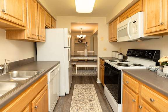 A kitchen with wooden cabinets and a white refrigerator  at Chapel Valley Townhomes, Maryland