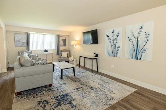 A living room with a couch, chair, and a rug.at Deer Park Apartments, Randallstown, MD 21133