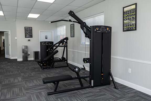 A gym with a rowing machine and a bench.