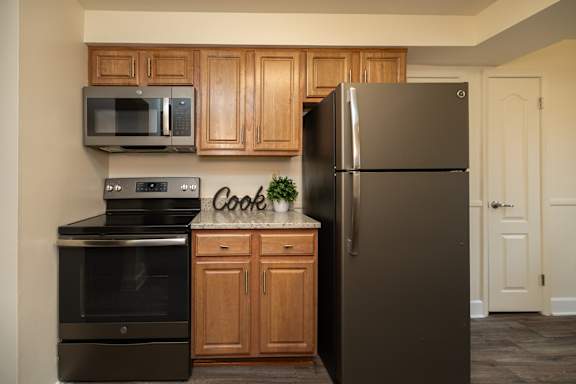 A kitchen with a black refrigerator, black oven, and black microwave.