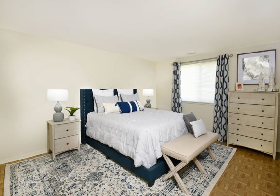 a bedroom with a bed with white and blue bedding and two night stands with lamps on