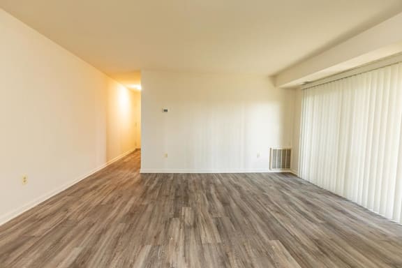 the living room and dining room of an empty house with wood flooring at Windsor House Apartments*, Baltimore