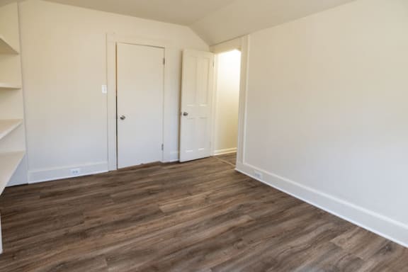 a bedroom with white walls and a wooden floor at Ivy Hall Apartments*, Towson, MD