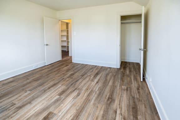 a bedroom with hardwood floors and white walls at Ivy Hall Apartments*, Towson, MD 21204