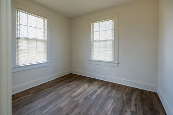 a bedroom with hardwood floors and two windows at Ivy Hall Apartments*, Towson, MD