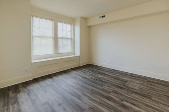 a bedroom with hardwood floors and two windows at Ivy Hall Apartments*, Towson, MD 21204